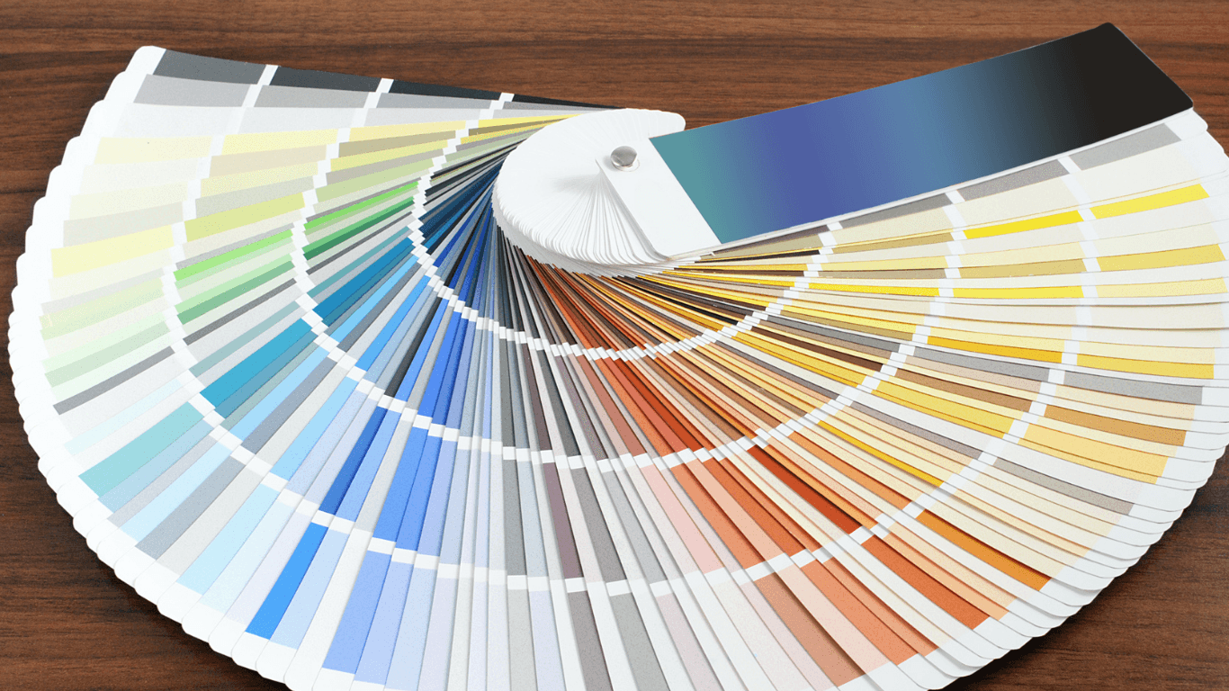 Paint color fan deck spread across a wood surface